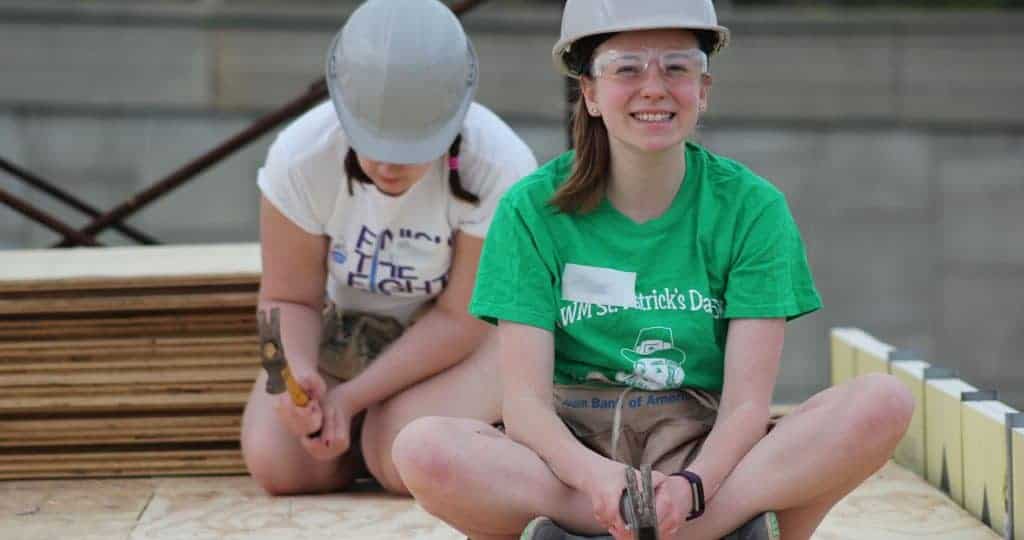 Young woman in hard hat with hammer