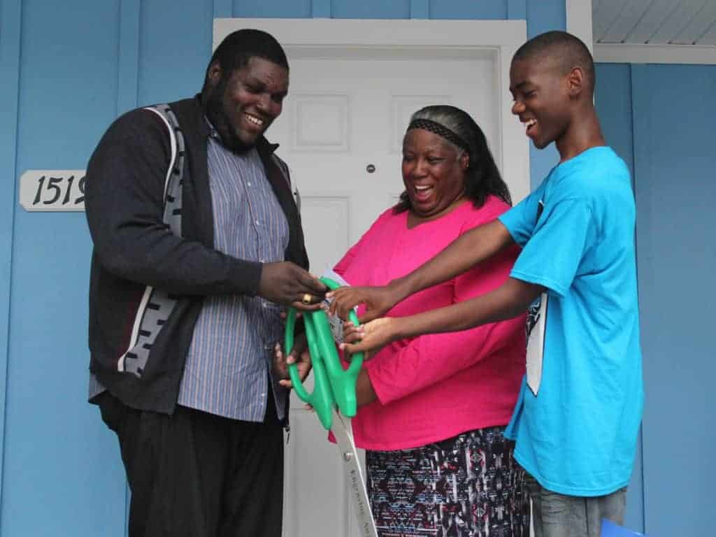 Mother and two sons cutting ribbon