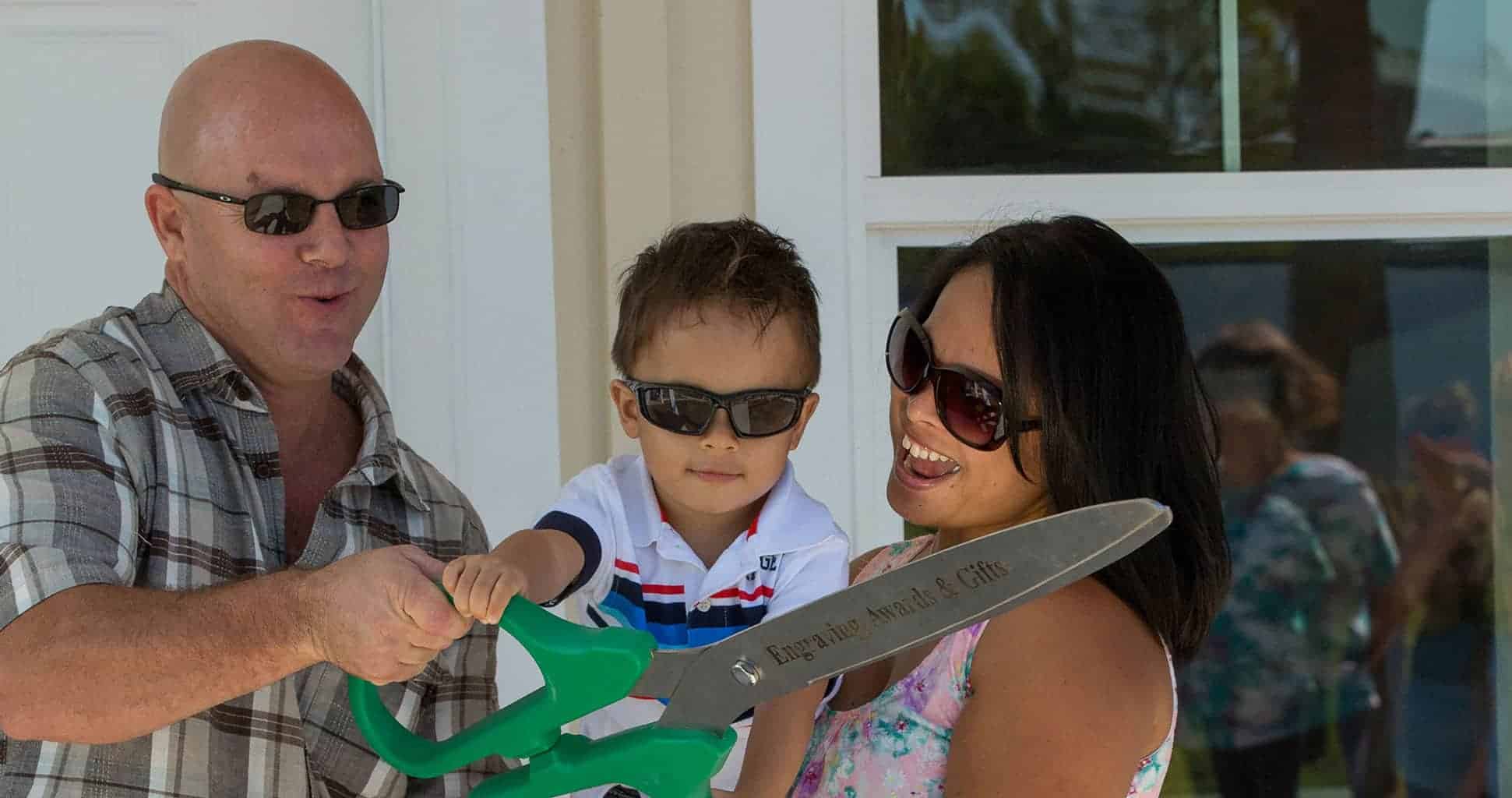 Family-Ribbon-Cutting Mother Father and Child holding large scissors