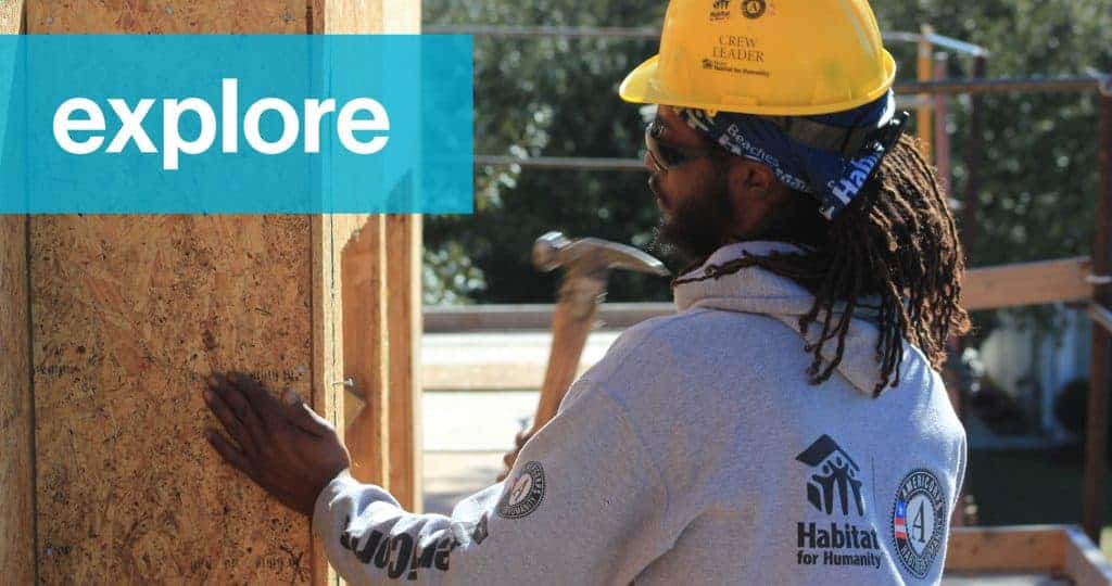 Young black man in hard hat swinging hammer