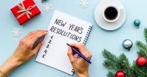 New Year's Resolutions written in notebook surrounded by Christmas decorations