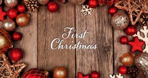 First Christmas written on wood surrounded by red and gold ornaments