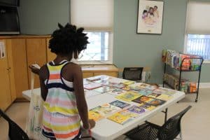 A young girls looks at a table full of books