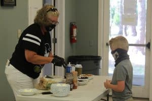 A volunteer serves a sundae to a young boy