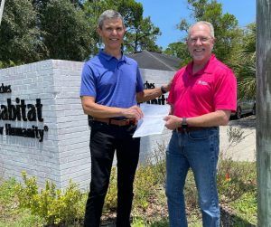 A member of Ponte Vedra Beach Rotary hands a check to Beaches Habitat CEO