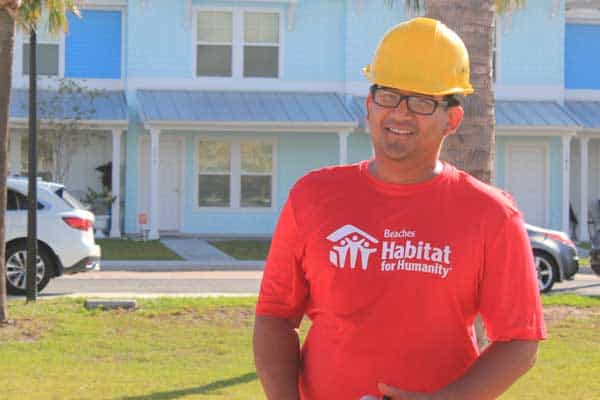 Man wearing hard hat standing in front of blue townhomes