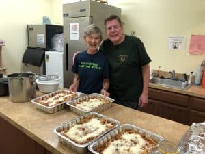A woman and man stand in a kitchen with trays of pasta