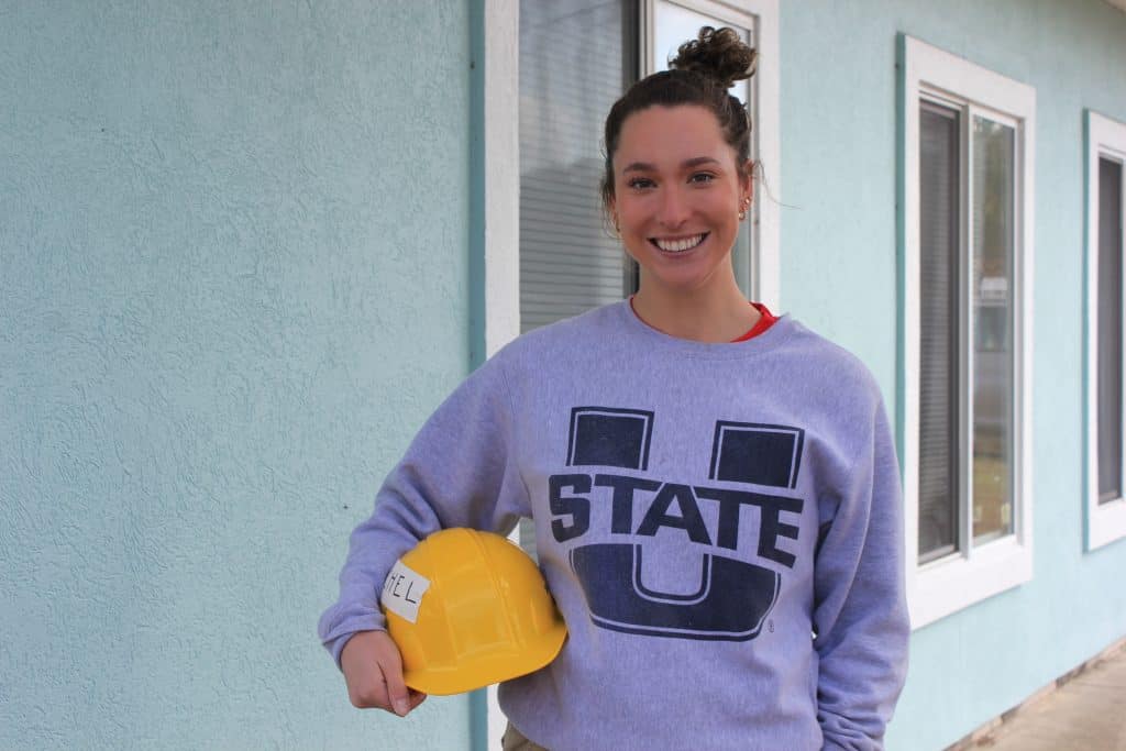 Young woman in Utah State Sweatshirt holding yellow hard hat