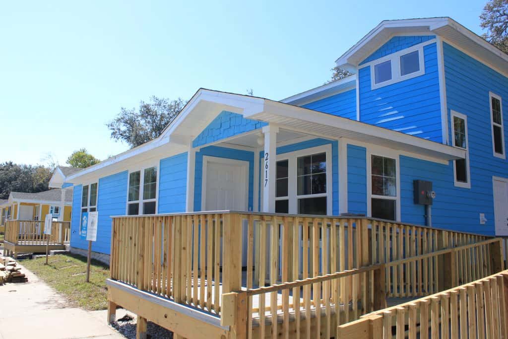 Front of two-story blue duplex that was built by Beaches Habitat and volunteers. Each house has wheelchair ramps leading up to the front door.