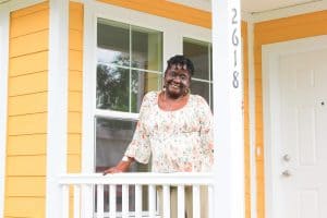Habitat homeowner standing proudly on the front porch of her new home.