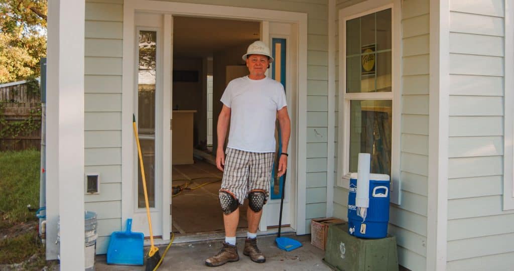 John a volunteer at Beaches Habitat standing in front of a house under construction.