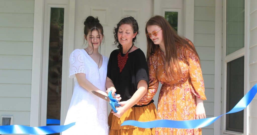 Mother and two daughters cutting ribbon