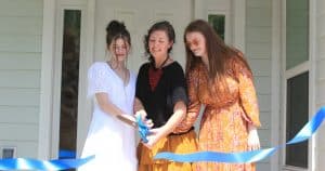 Mother and two daughters cutting ribbon