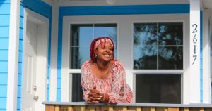 Smiling woman leaning on railing of front porch