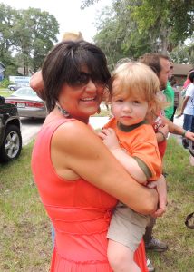 Debbie smiling and holding a young child at a Beaches Habitat event.