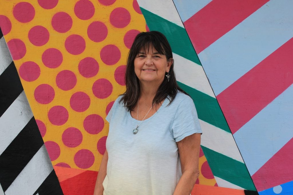 Debbie smiling in front of a colorful mural.