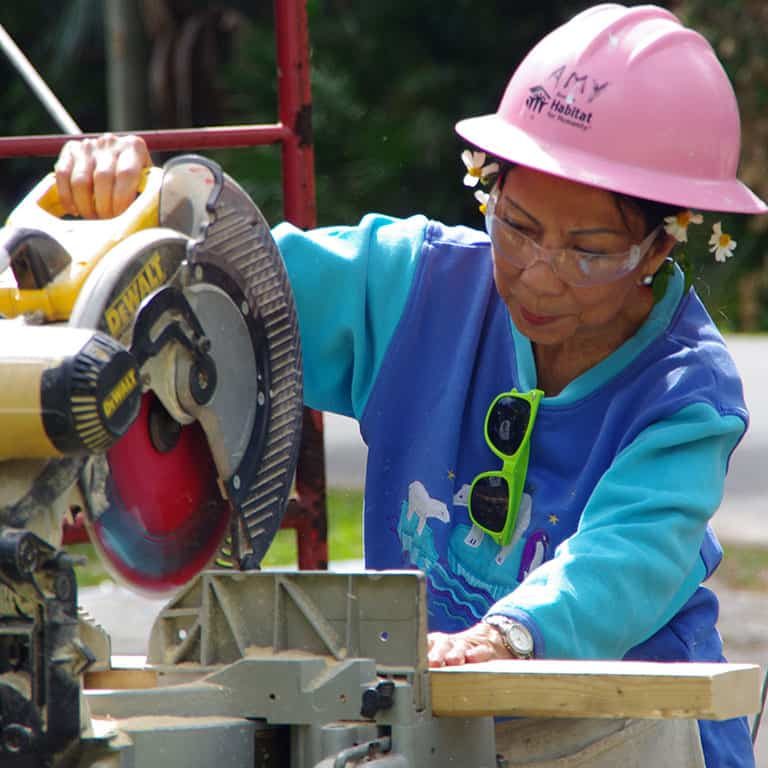 Women in pink hard hat using saw