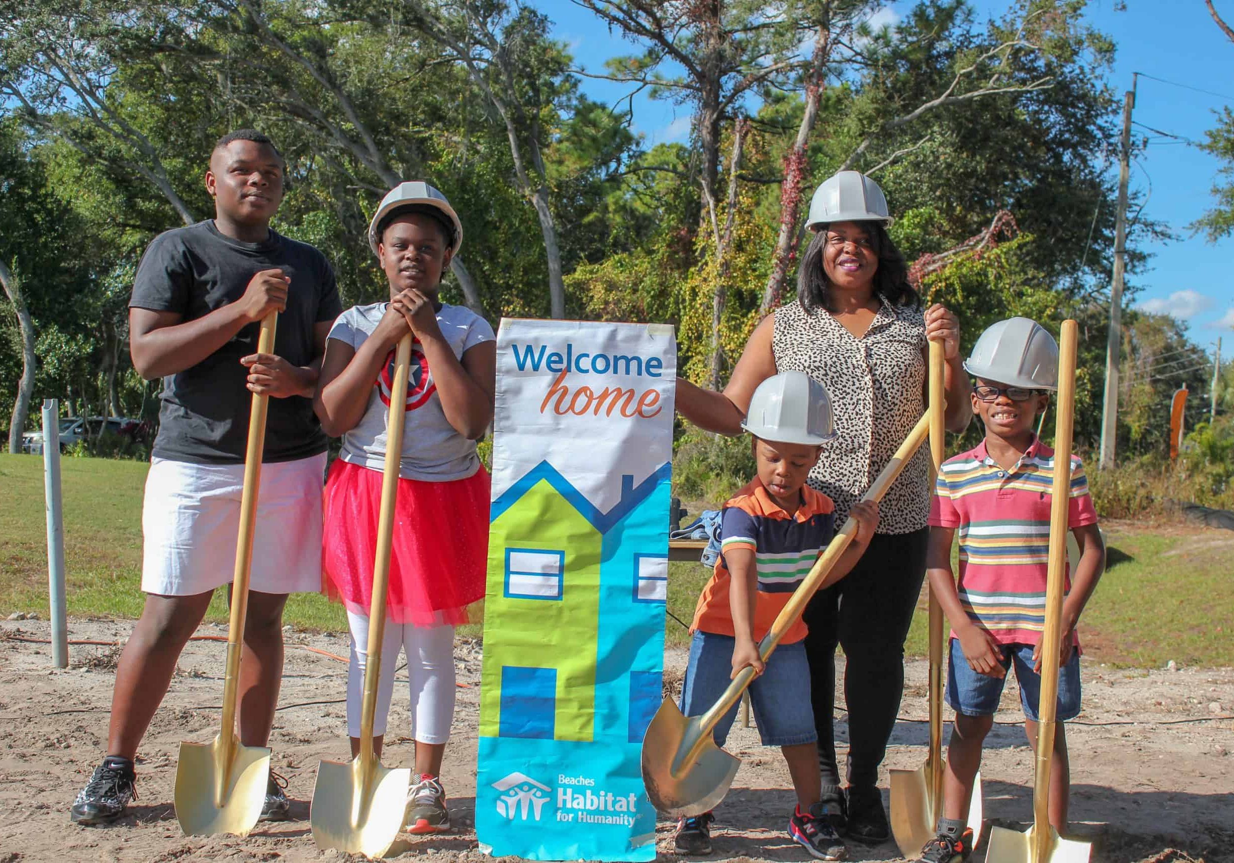 Family holding shovels wearing hard hats